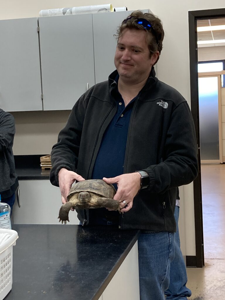 Man on blue shirt holding a turtle